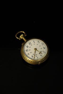 a gold pocket watch sitting on a black surface