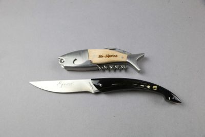two knives and a fish shaped bottle opener on a table