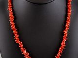 a red coral beaded necklace on a black mannequin