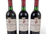 three bottles of red wine sitting next to each other on a white surface