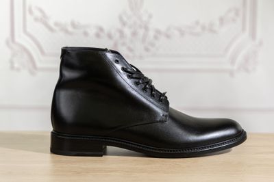 a close up of a pair of black leather boots on a wooden table
