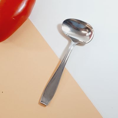 a spoon and a tomato sitting on a table