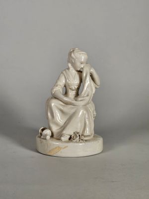 statue d'une femme assise sur un rocher, tenant un oiseau dans la main