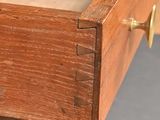 close up of a wooden drawer with brass handles on a gray floor
