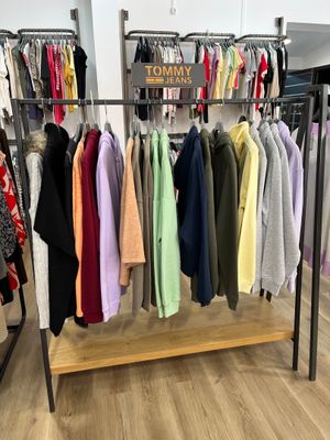 des vêtements suspendus à un portemanteau dans un magasin de vêtements, sur un sol en bois