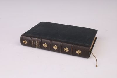 un vieux livre à la couverture noire posé sur une table blanche