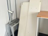 a room with a desk, refrigerator, and other items in it