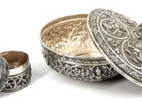 a silver box with a lid sitting next to a ring