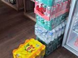 many bottles of water sitting on the floor next to a refrigerator