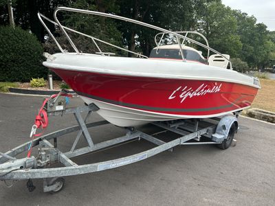 un bateau rouge et blanc sur une remorque dans un parking
