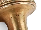 a close up of a gold vase on a white surface