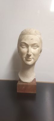 a white marble head of a woman on a wooden stand