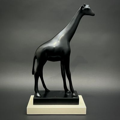 statue d'une girafe debout sur un socle, sur fond gris