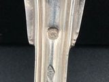 an antique silver spoon with a handle on a black surface