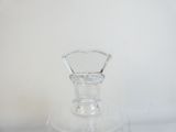 un vase en verre transparent avec un socle transparent posé sur une surface blanche