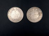 two silver coins on a black surface with a black background
