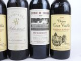 three bottles of red wine are lined up on a white surface