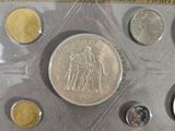 an assortment of silver and gold coins in a plastic case