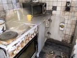 a dirty kitchen with a stove and a microwave in it
