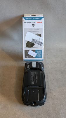 un téléphone portable noir posé sur une table à côté d'un colis