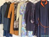 un grand nombre de robes suspendues à une étagère dans une pièce