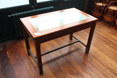 une petite table avec un plateau en verre posée sur un parquet