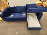 a blue couch with a pull out bed in the middle of a room
