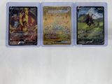 three different pokemon trading cards in plastic cases on a white surface