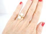a woman ' s hand with a red manicure and a pearl ring on it