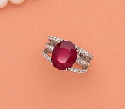 un gros plan d'une bague ornée d'une pierre rouge entourée de perles