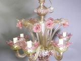 un lustre en verre duquel pendent des fleurs roses, suspendu au plafond