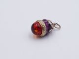 a close up of a red and purple glass bead on a silver chain