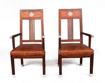 paire de chaises en bois avec des assises rembourrées de cuir, montées sur roulettes
