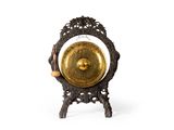 un gong doré posé sur un socle, sur une surface blanche