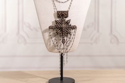 Collier avec une croix en perles, présenté sur un mannequin devant un fond blanc