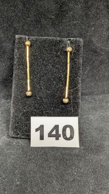 un gros plan sur une paire de boucles d'oreilles en or posées sur un tissu noir