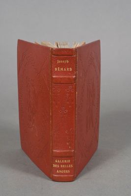an old red book sitting on top of a table next to a gray wall
