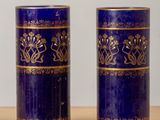 une paire de vases bleus ornés de motifs dorés, posés sur une table