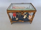 une boîte en verre posée sur une table, contenant des figurines