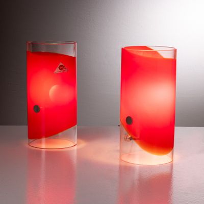 two glass vases with red liquid in them on a table