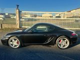 une voiture de sport noire garée devant un parking fermé par un portail