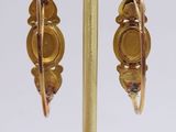 a close up of a pair of earrings on a gold stand