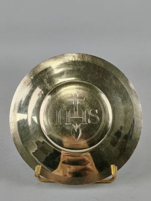 une image représentant une assiette en or posée sur un socle, sur fond gris