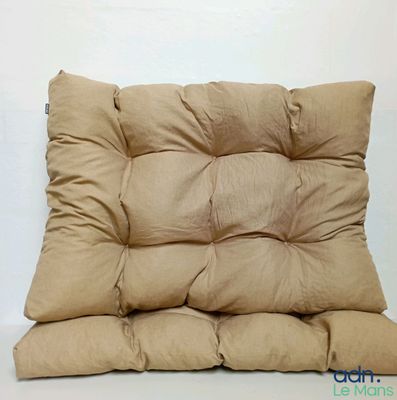 a tan cushion on a white table with a white wall in the background