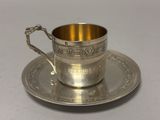 an antique silver cup and saucer on a saucer on a white surface
