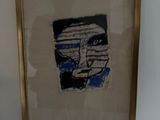 painting of a man ' s face in a gold frame on a white wall