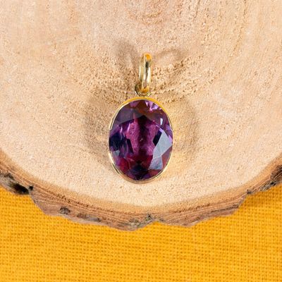 a close up of a purple stone pendant on a piece of wood