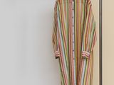 striped shirt hanging on a clothes rack in front of a yellow wall