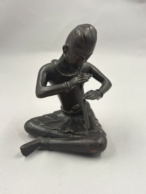 une image représentant une statue en bronze d'un homme assis à genoux