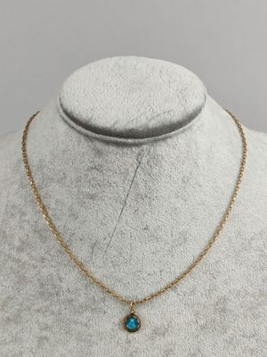 a gold necklace with a blue stone on a mannequin mannequin
